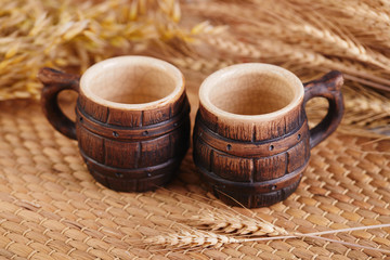 Beer clay cup and beer glass with wheat ears on rustic table