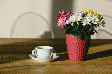 A cup of tea on a table next to a beautiful flower pot.