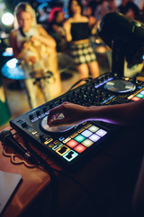 DJ plays live set and mixing music on turntable console at stage in the night club. Disc Jokey...