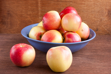 apples in a blue clay bowl on a wooden table