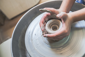 Child hands working with clay on pottery wheel