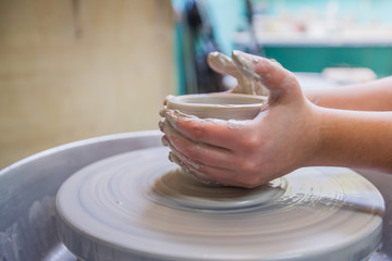 Child hands working with clay on pottery wheel