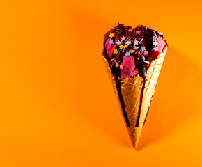 Pink ice cream in waffle cone lying on background