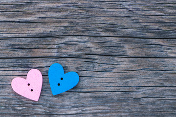 Two hearts (pink and blue) in the corner of the image on a wooden surface. Background to the Valentine's day and wedding.
