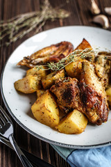 Baked chicken wings with potatoes and garlic on a rustic background