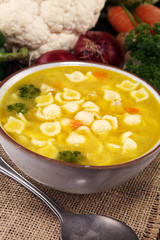Clear soup with chicken and noodles. Broth with carrots, onions various fresh vegetables in a pot