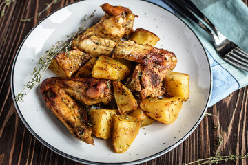 Baked chicken wings with potatoes and garlic on a rustic background
