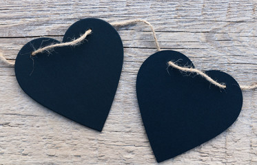 Two black hearts on a wooden surface. Background to the Valentine's day and wedding.
