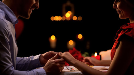 Man holding womans hand, proposing marriage during romantic date, relations