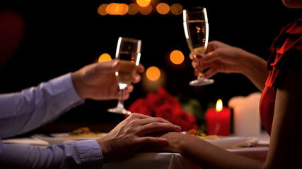 Couple drinking champagne, male stroking lady hand tenderly, romantic evening