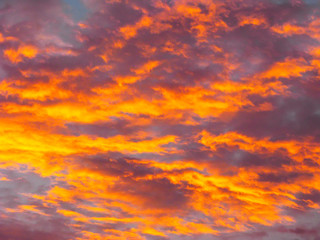 Dramatic sunset sky background with fiery clouds, yellow, orange and pink colors