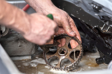 Car mechanic is cleaning and mantaining gear .