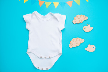 mockup Flat Lay a white baby shirt with wooden toys on a blue background. Layout for the design and...