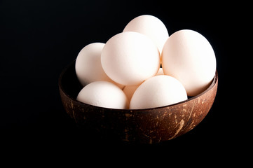 Fresh eggs in the bowl on the black background