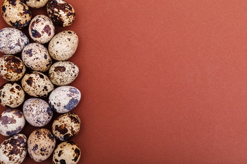 Quail eggs on a brown solid background, top view, copy space. Healthy food, Holidays, nature concept. Easter Background