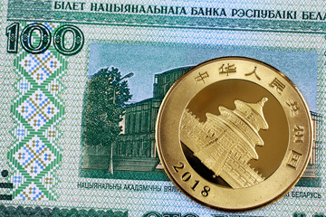 A blue, one hundred Belorussian bank note with a Chinese one ounce gold panda coin