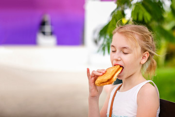 Blonde girl s having a lunch in the summer park of entertainments on the playground