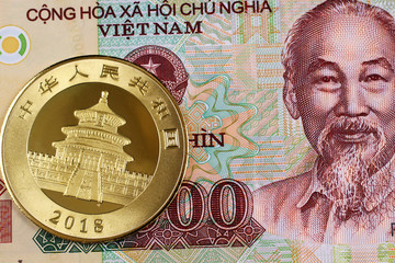 A colorful ten thousand Vietnamese dong note with a Chinese one ounce gold coin