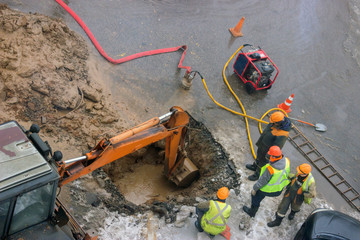 A group of road workers from public utilities in reflective special vests are discussing an...