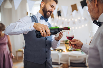 A man pouring guests wine on a indoor family birthday party.