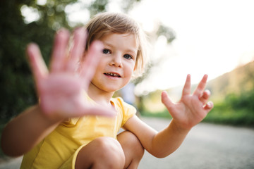 A small cute girl on a road in countryside in sunny summer nature.