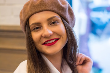 Beautiful girl in a beret sits near the window in a cafe