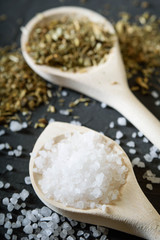  Wooden spoon with Italian seasoning-dried oregano with thyme,vegetables.Oregano in a wooden spoon on a rocky concrete dark black background with a place for text Top view