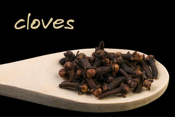 cloves on wooden spoon isolated on black background