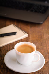  Laptop (notebook) mobile phone (smartphone) and notepad with pen on old wooden table. Work place modern.Cup of coffee