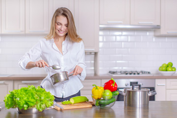 Happy young girl preparing healthy food in the kitchen