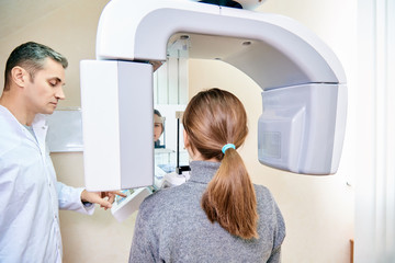 dental tomography. Girl-patient stands in a tomograph, a doctor near the control panel