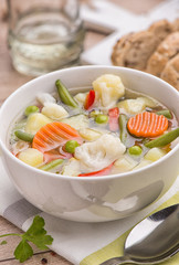 Vegetable vegetarian soup in a white deep plate on a striped substrate.