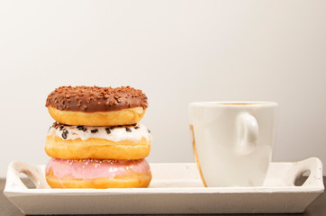 three donuts on a white tray with a cup of coffee, white background