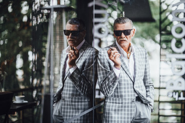 Italian stylish senior smoking expensive cigarette at summer terrace .He is wearing at modern suit