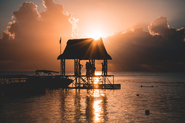 Beautiful sunset in Trou aux Biches, Mauritius. View of the jetty and boats amidst palm trees
