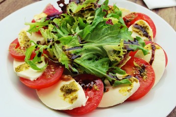 Tomato, Mozzarella Cheese, vinaigrette Salad on a white Plate