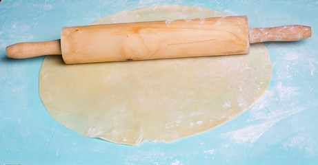 Wooden rolling pin with flour and dough.
