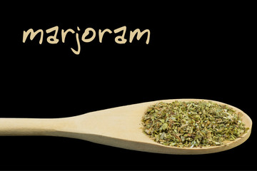 marjoram on wooden spoon isolated on black background