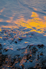 Colorful sunset on the sea. Close up white foam on the shore. Beautiful nature.