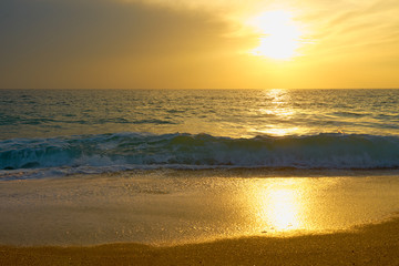 Obraz premium Tropical sandy beach. Sunset seascape. Waves with foam hitting sand.