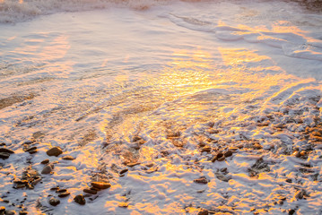 Colorful sunset on the sea. Close up white foam on the shore. Beautiful nature.