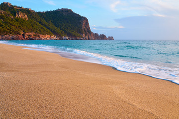 Fototapeta premium Alanya Castle (Alanya Kalesi) on the top of peninsula. View on sea from sandy Cleopatra Beach, Alanya, Turkey in evening. 