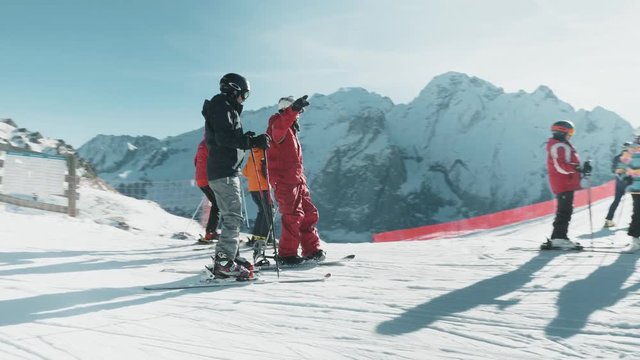 A young family gets off a ski lift at the top of the hill. Shot at the Dolomites ski hills in Belluno, Italy.