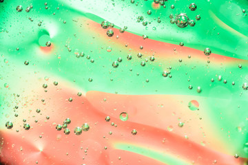 oil bubbles in water close up on a red green background