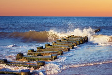 Wood pier post in Maryland Beach with rolling waves.  with Orange sky