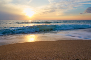 Fototapeta na wymiar Tropical sandy beach. Sunset seascape. Waves with foam hitting sand.
