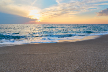  Tropical sandy beach. Sunset seascape. Waves with foam hitting sand.