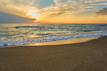 Fototapeta premium Tropical sandy beach. Sunset seascape. Waves with foam hitting sand.