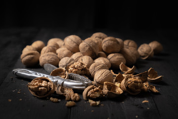 Walnuts on dark background. Low-key image of nuts on black rustic table, artistic light and shadow technique