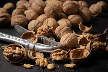 Walnuts on dark background. Low-key image of nuts on black rustic table, artistic light and shadow...